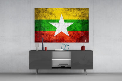Myanmar flag glass wall art with yellow, green, and red horizontal stripes and white star displayed above gray media console.