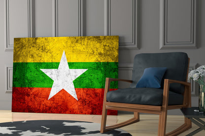Myanmar flag glass wall art displaying yellow, green, and red horizontal stripes with white star, positioned in modern living room beside wooden chair.