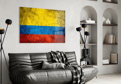 Colombian flag glass wall art displayed above black leather sofa in modern living room with shelving.