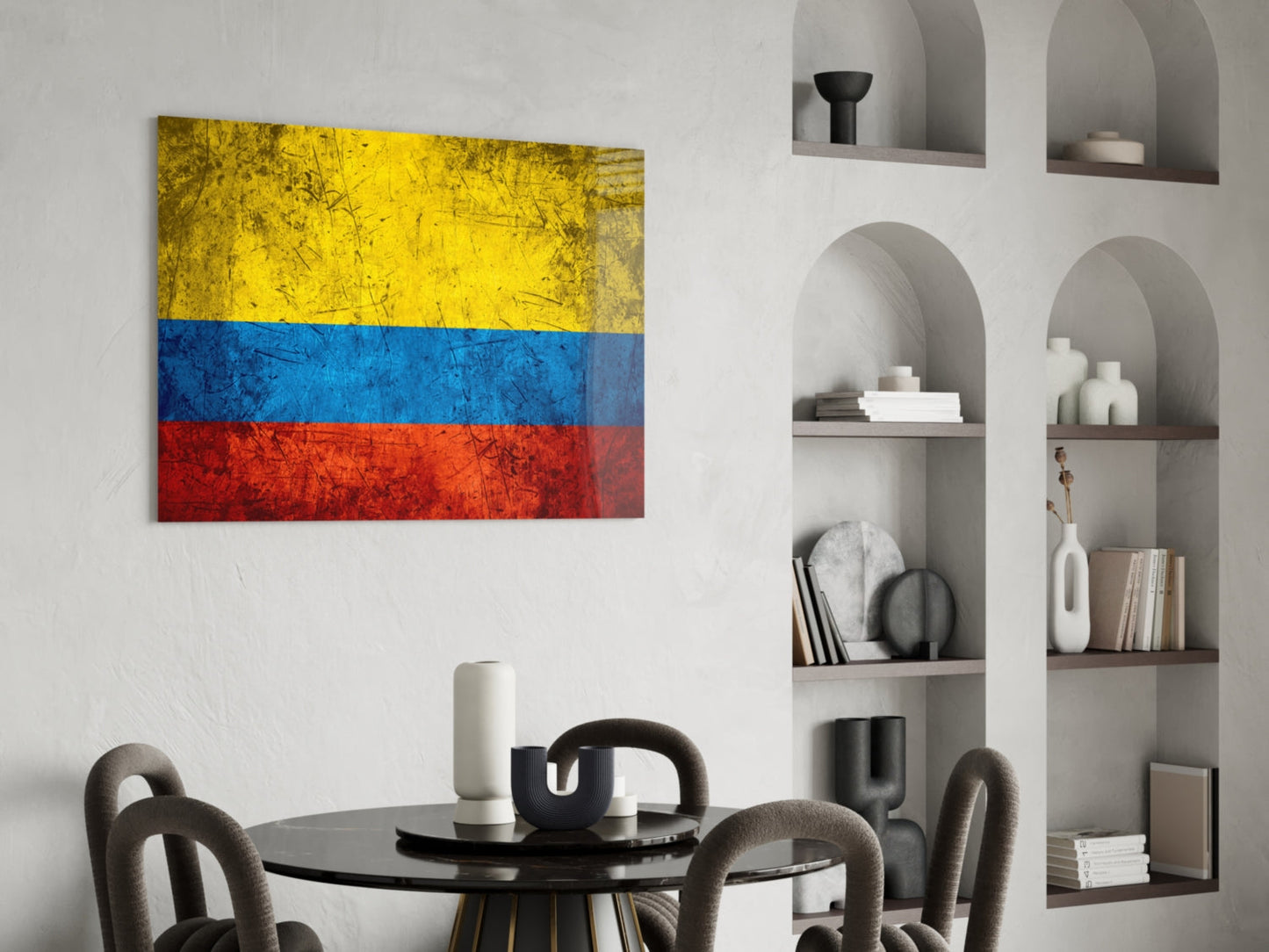 Colombian flag glass wall art displayed above a round black dining table with gray chairs and white sculptural decor.