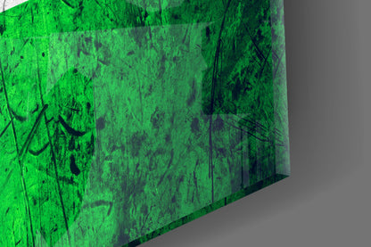 Close-up angled view of vibrant green glass with black handwritten marks and scratches visible on the surface.
