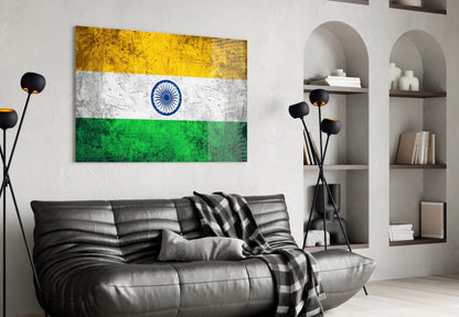 Indian flag glass wall art with yellow, white, and green horizontal stripes and blue ashoka chakra displayed above black leather sofa in modern living room.