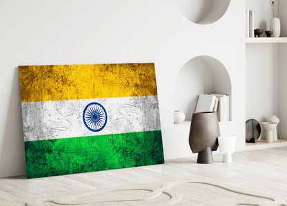 Indian flag glass wall art leaning against white wall in minimalist interior with decorative objects and shelving.