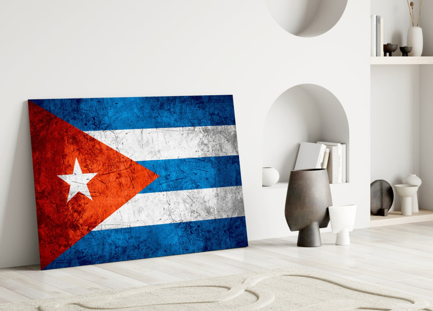 Cuban flag glass wall art leaning against white wall in minimalist interior with decorative objects and shelving.