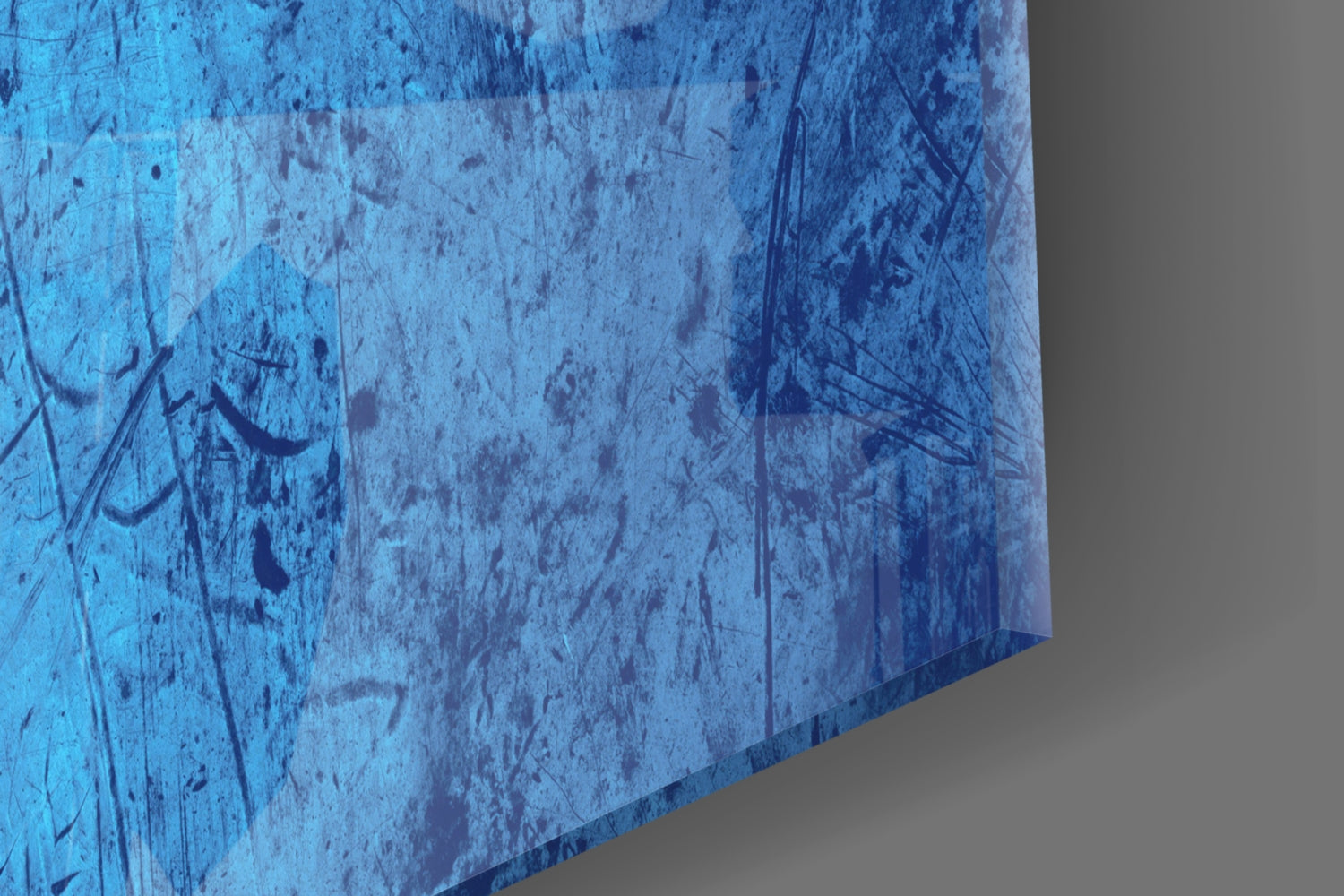 Close-up detail of blue glass surface with scratches and distressed texture, showing edge perspective against gray background.