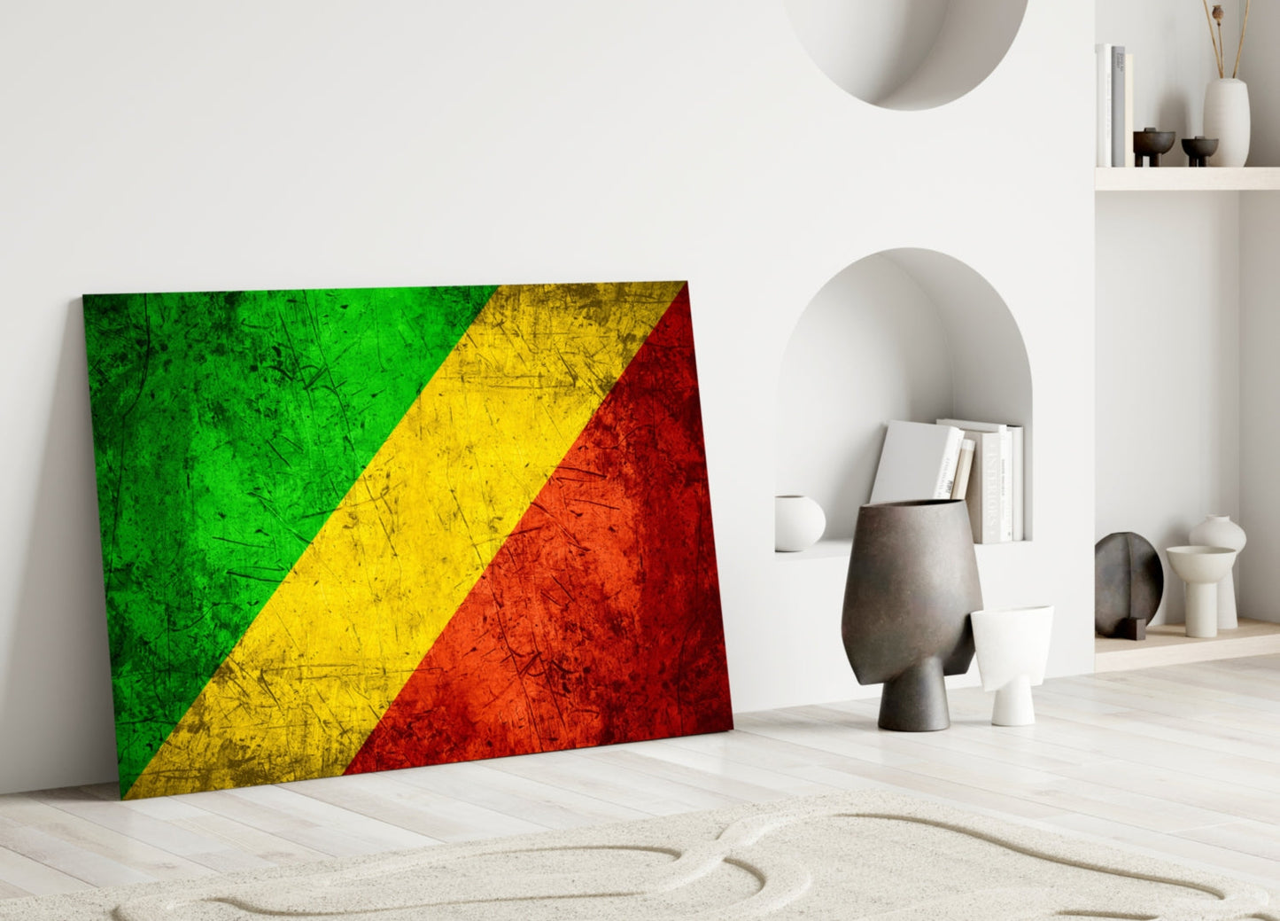 Congolese flag glass wall art leaning against white wall in minimalist interior with shelving and decorative objects.