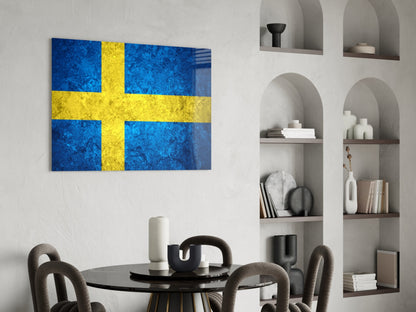 Swedish flag glass wall art with blue and yellow cross displayed above round black dining table in modern interior.