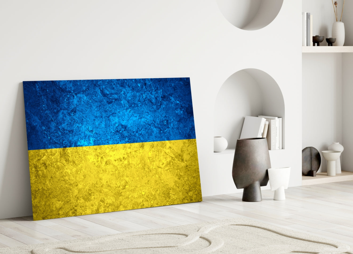 Ukrainian flag glass wall art leaning against white wall in minimalist room setting with decorative objects.