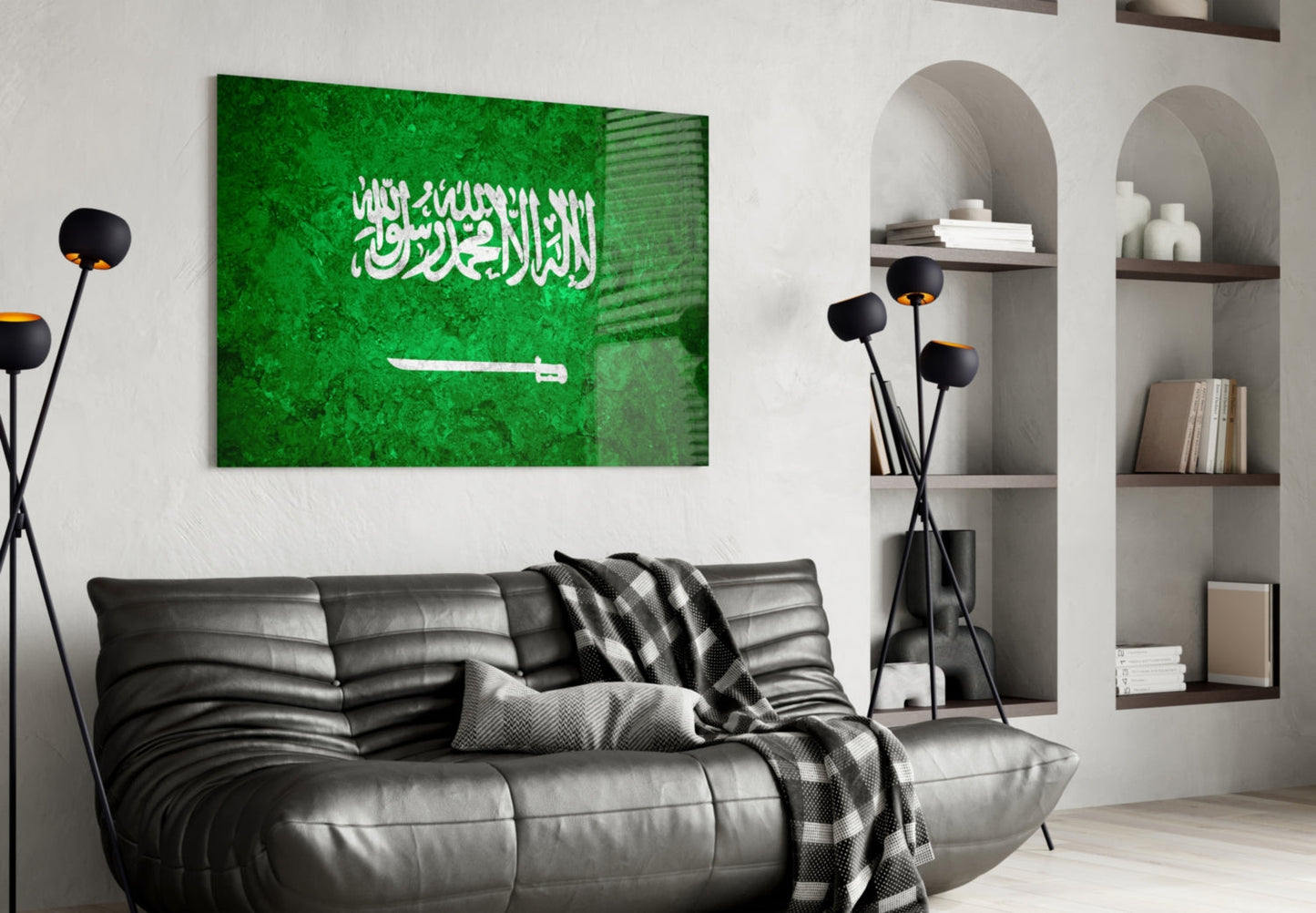 Green glass wall art displaying white Arabic text and sword emblem of Saudi Arabia flag, mounted above black leather sofa in modern living room.