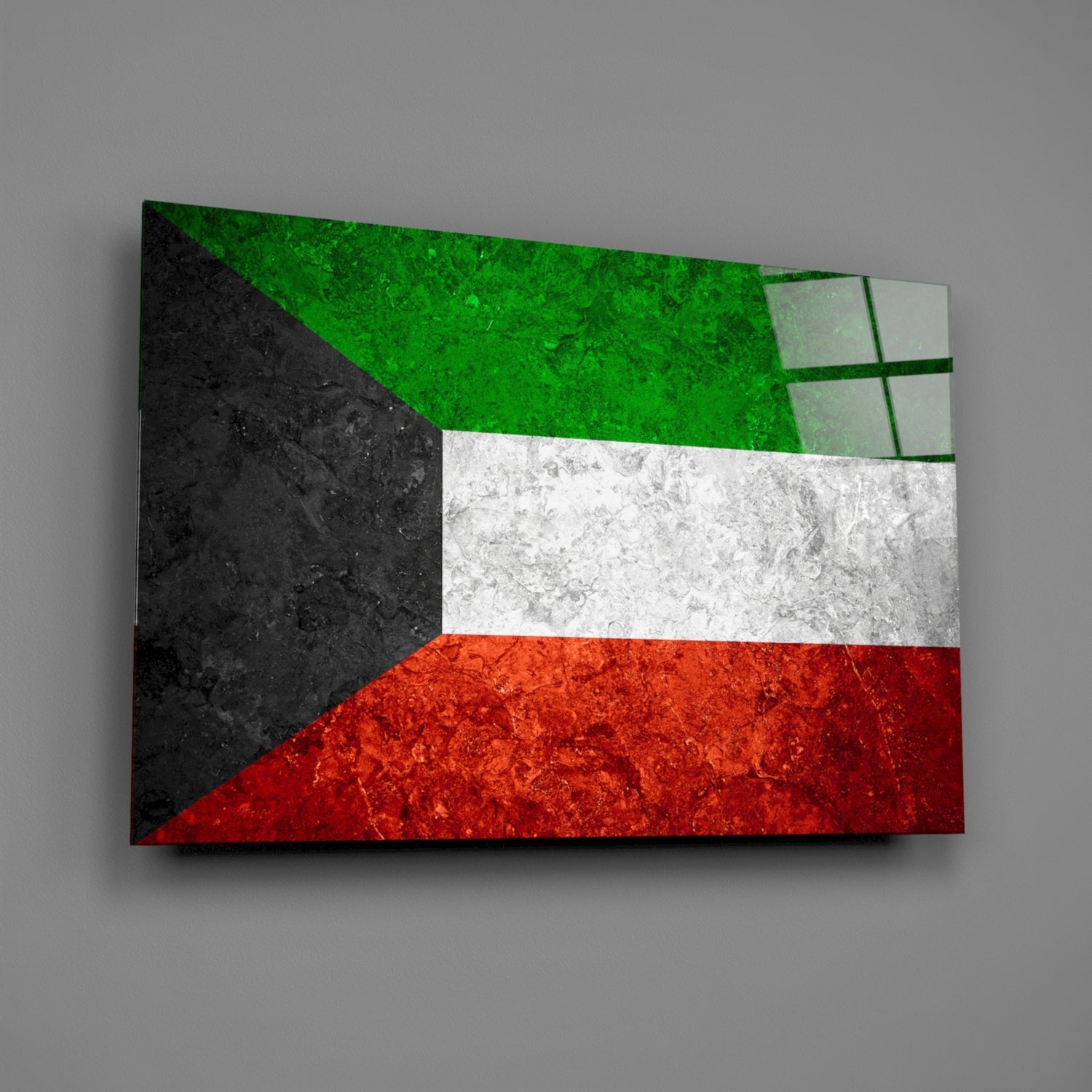 Angled view of Kuwait flag glass wall art showing green, white, and red horizontal stripes with black triangle, mounted on gray wall.