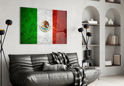 Mexican flag glass wall art with green, white, and red vertical stripes and eagle emblem displayed above black leather sofa in modern living room.