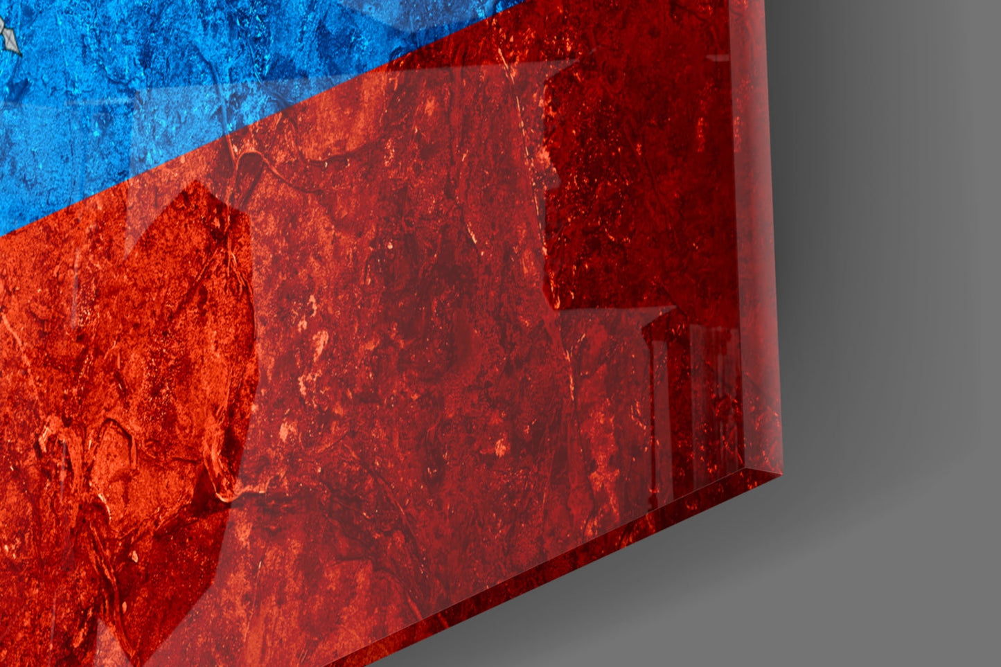 Close-up angled view of Ecuador flag glass art showing bright blue and red sections with textured glass surface and shadow detail.