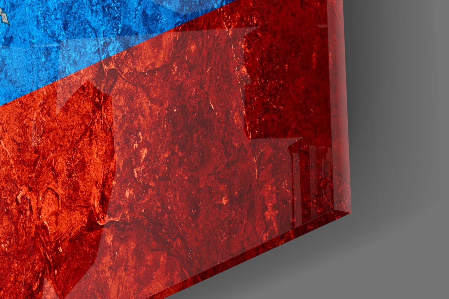 Close-up angled view of Ecuador flag glass art showing bright blue and red sections with textured glass surface and shadow detail.