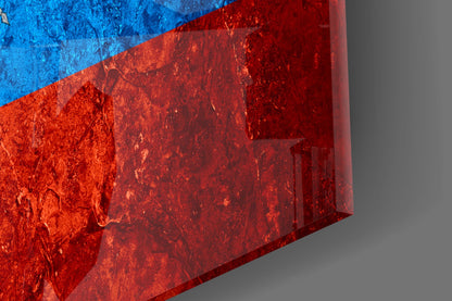 Close-up angled view of Ecuador flag glass art showing bright blue and red sections with textured glass surface and shadow detail.