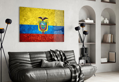Ecuador flag glass wall art displaying yellow, blue, and red horizontal stripes with coat of arms, hung above black leather sofa in modern living room.