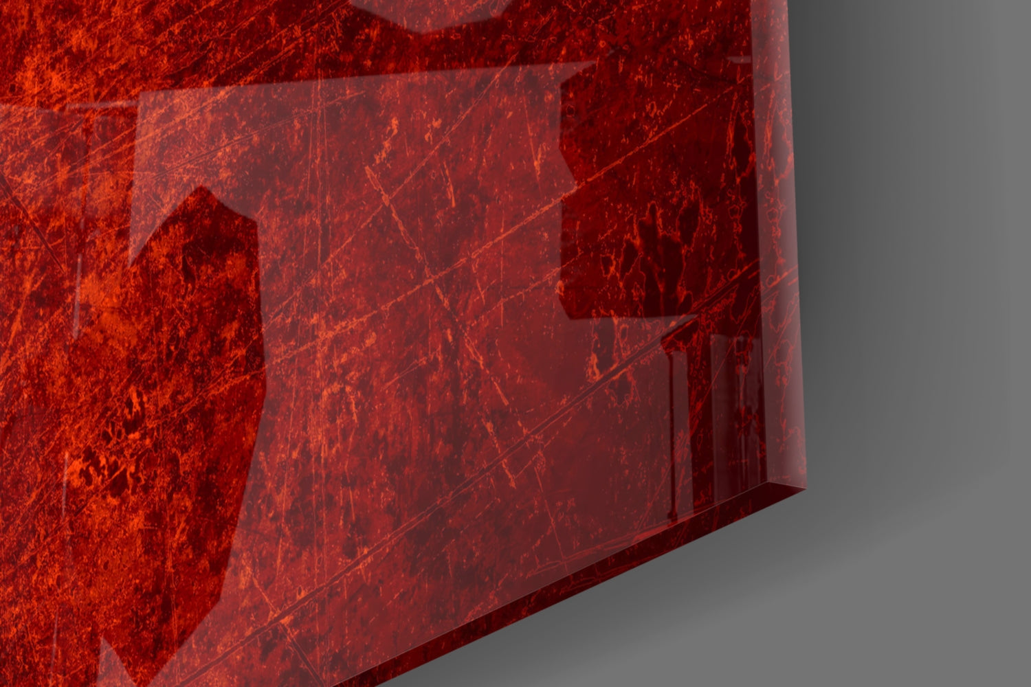 Close-up angled view of red textured glass panel with visible scratches and wear marks against gray background.