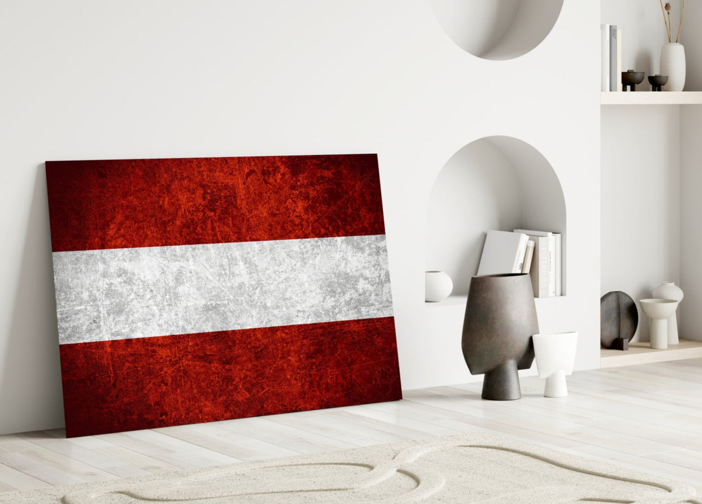 Austrian flag glass wall art leaning against white wall in minimalist room with decorative objects.