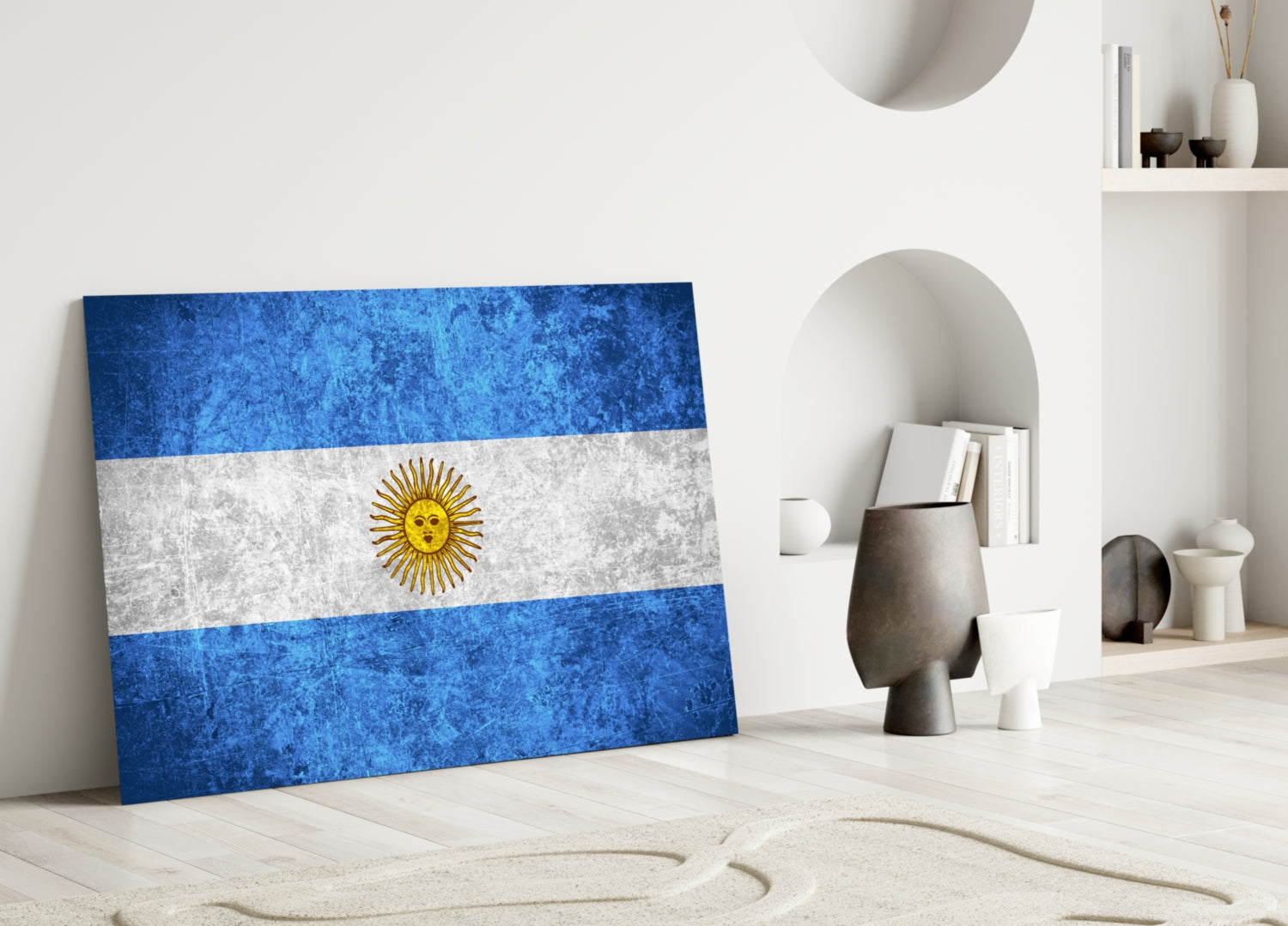 Argentine flag glass wall art leaning against white wall in minimalist room with decorative objects.