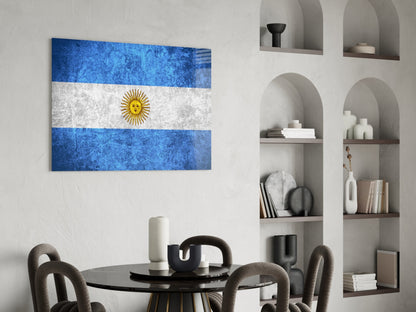 Argentine flag glass wall art displaying blue, white, and gold sun stripes displayed above dining table in modern interior.
