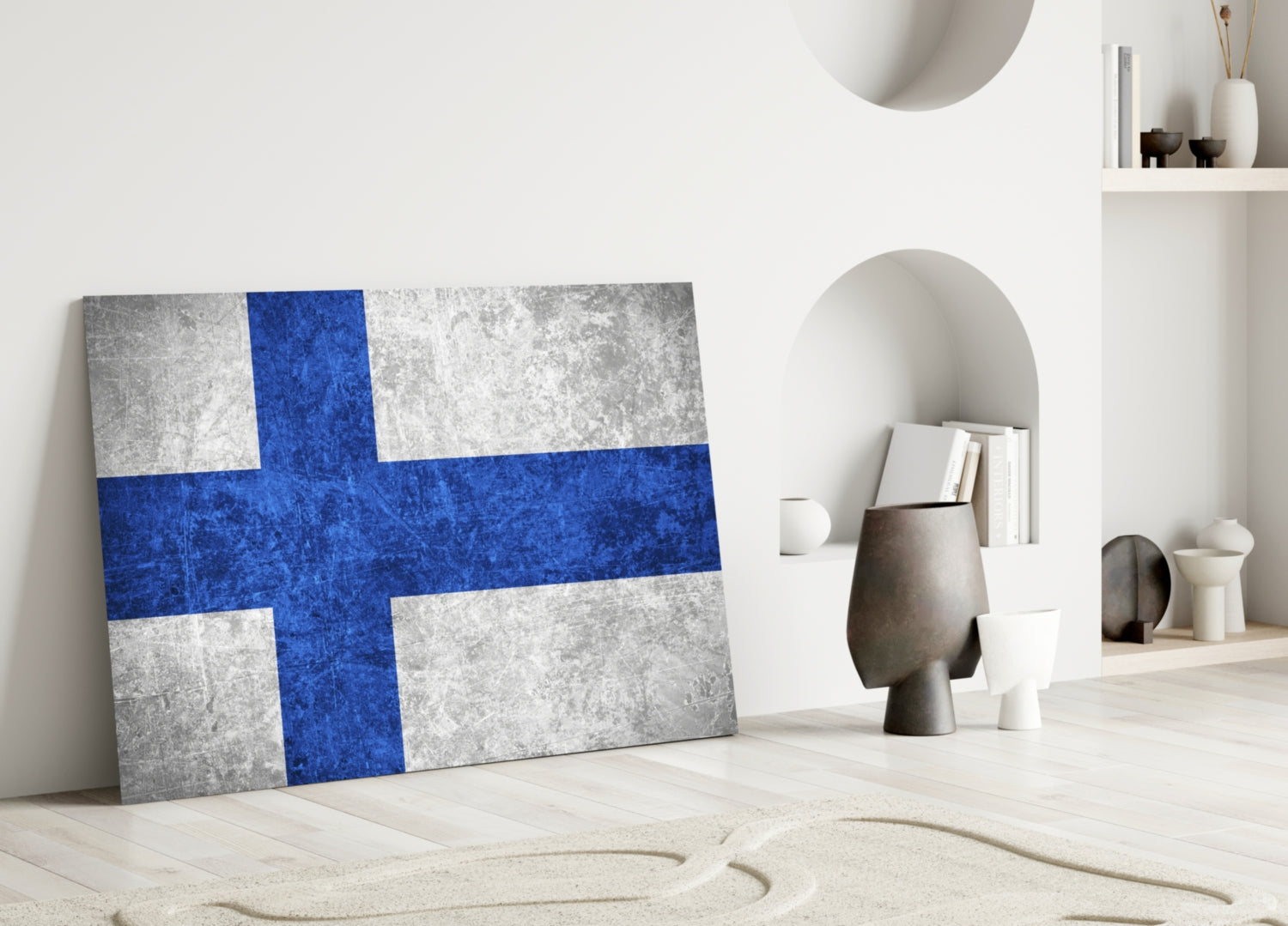 Finnish flag glass wall art leaning against white wall in minimalist interior setting with decorative objects.