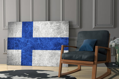 Finnish flag glass wall art displayed in a modern living room beside a wooden chair with blue cushions.