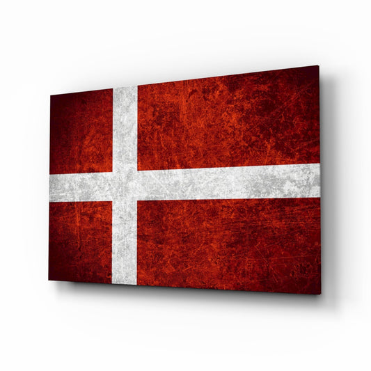 Deep burgundy and white Danish flag glass panel displayed at a tilted angle against a light background, showing weathered texture.