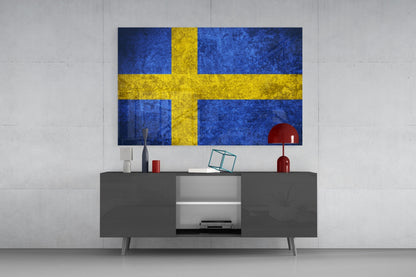 Swedish flag glass wall art mounted above gray media console in modern living room setting.