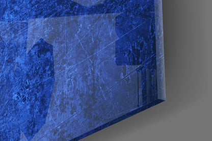 Close-up angled view of blue glass wall art with scratched surface texture and subtle darker blue tones, shown against gray background.