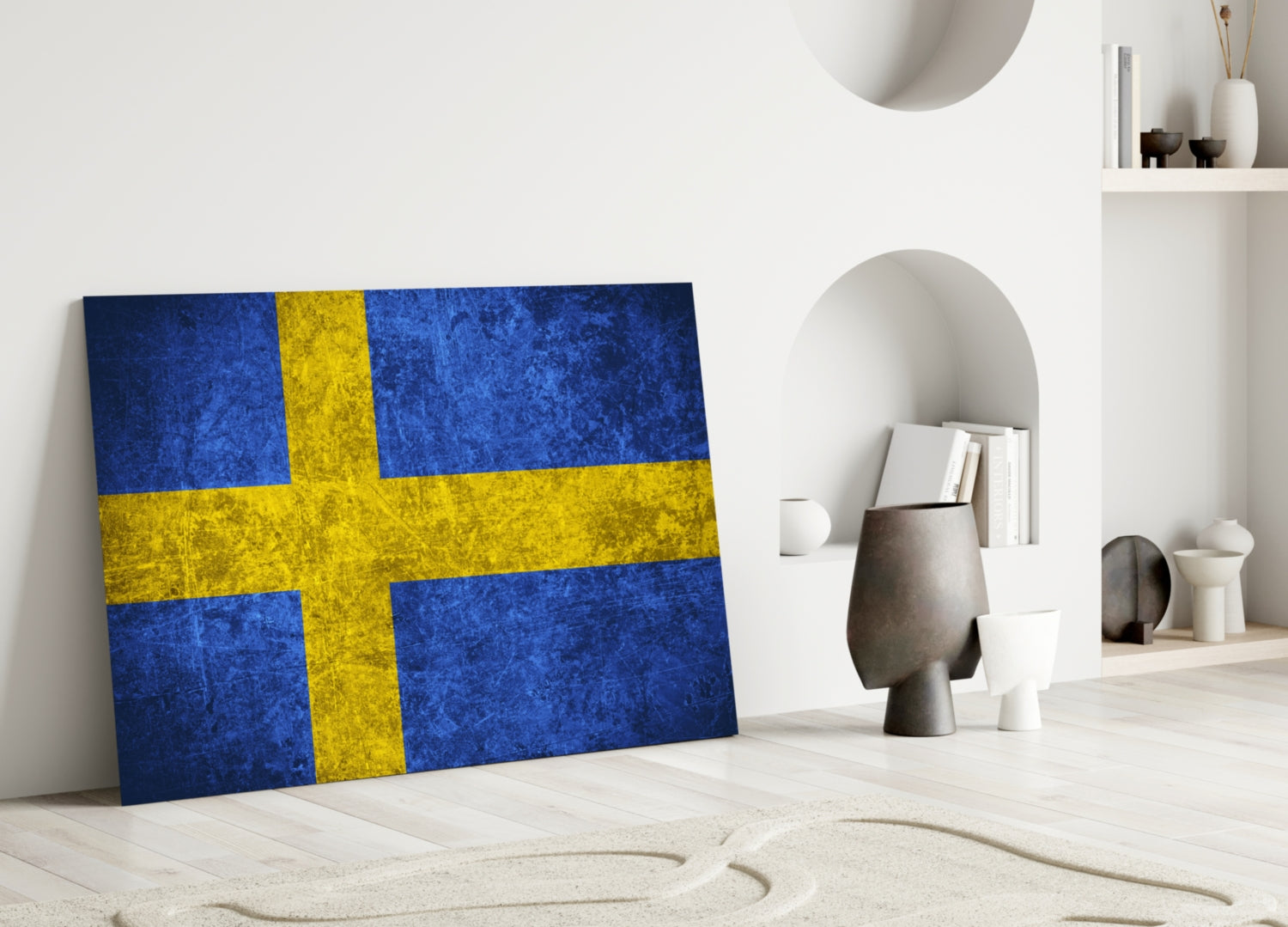 Swedish flag glass wall art leaning against white wall in minimalist interior with decorative objects and shelving.