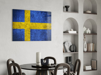 Swedish flag glass wall art with blue and yellow cross displayed above a dining table in a modern interior setting.