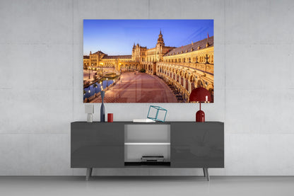Sevilla Glass Wall Art displaying illuminated golden architecture mounted above dark gray media console with decorative accessories.
