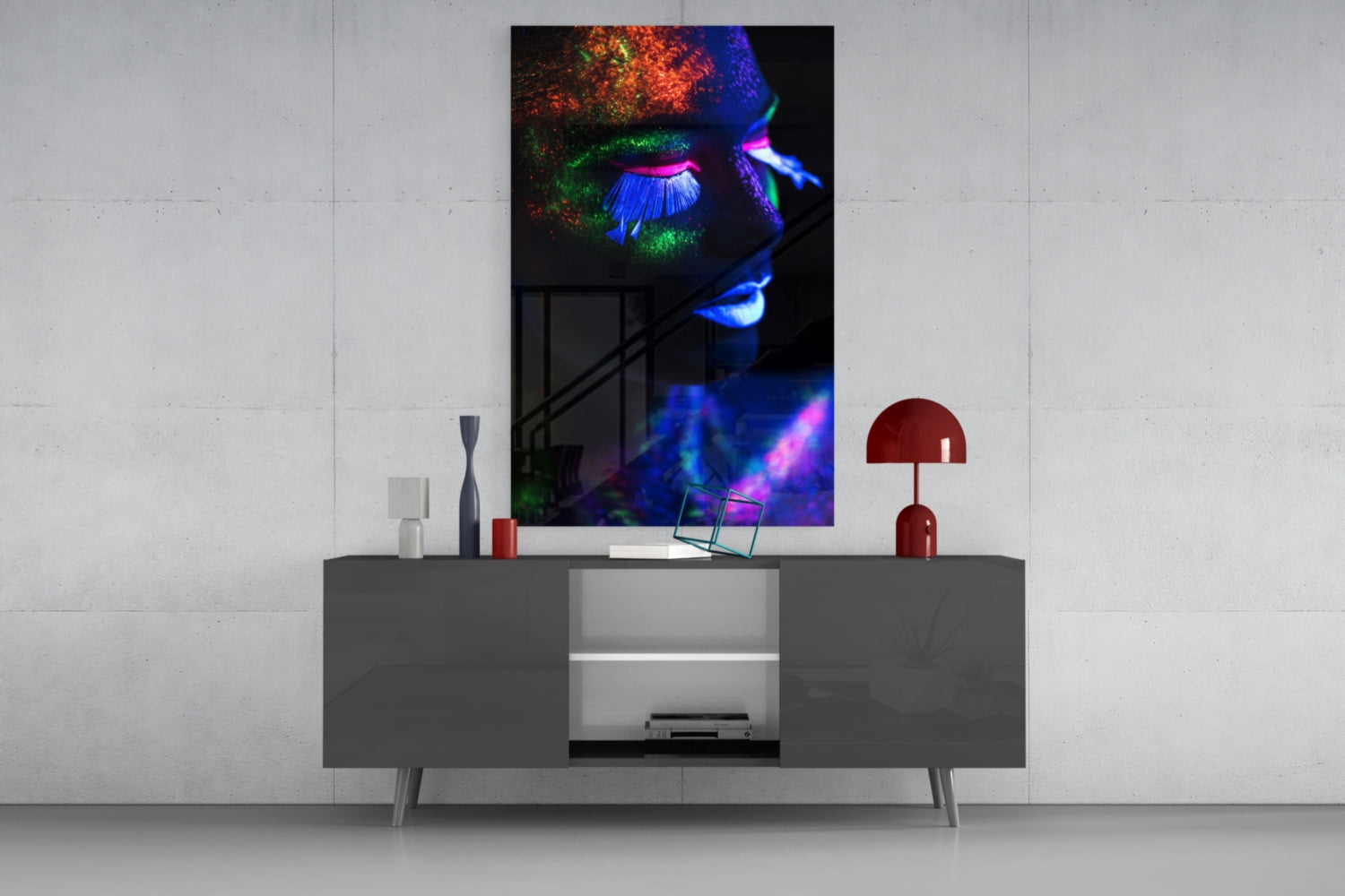 Neon makeup glass wall art featuring vibrant blue, green, pink, and orange fluorescent colors on black background, displayed above gray media console in modern interior setting.