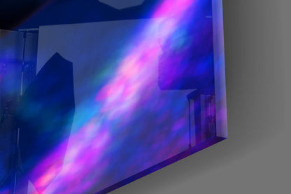 Neon makeup glass wall art illuminated with vibrant pink, blue, and purple light beams crossing diagonally across white gallery walls.