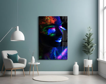 Neon makeup glass wall art displaying a face with fluorescent orange, green, and blue paint in a modern living room setting.