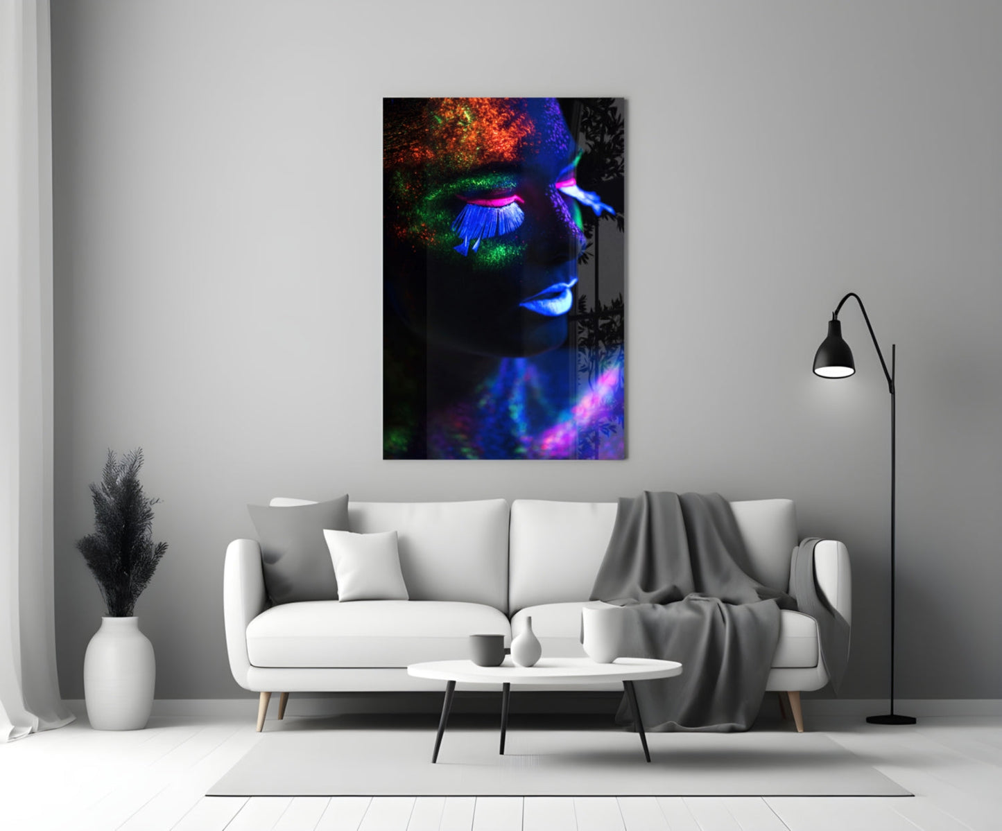 Neon makeup glass wall art displaying a face with fluorescent orange, green, and blue pigments against black background, hung above white sofa in modern living room.