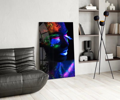 Neon makeup glass wall art leaning against wall in modern living room with gray sofa and shelving unit.