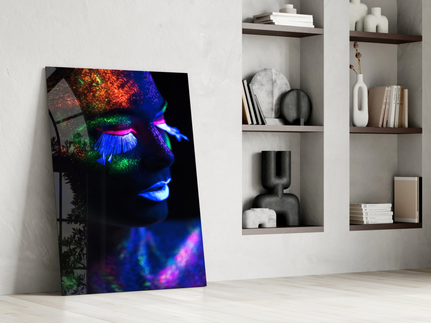Neon makeup glass wall art leaning against white wall beside shelving unit, displaying vibrant blue, pink, green, and orange fluorescent face design.