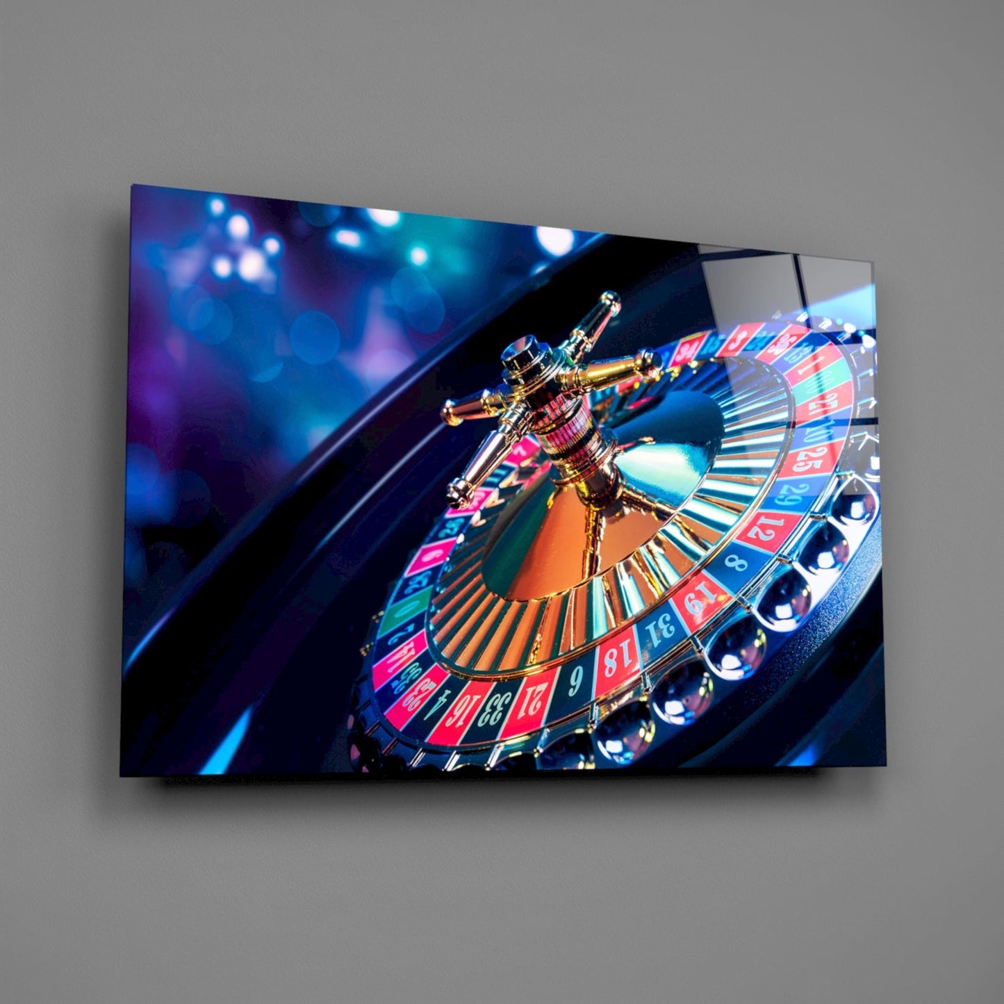 Glass wall art displaying a close-up roulette wheel with golden spindle, red and blue numbered sections, mounted on gray wall.