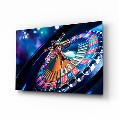 Angled view of glass wall art depicting a gold roulette wheel with red and blue numbered sections against dark blue background with bokeh lighting.