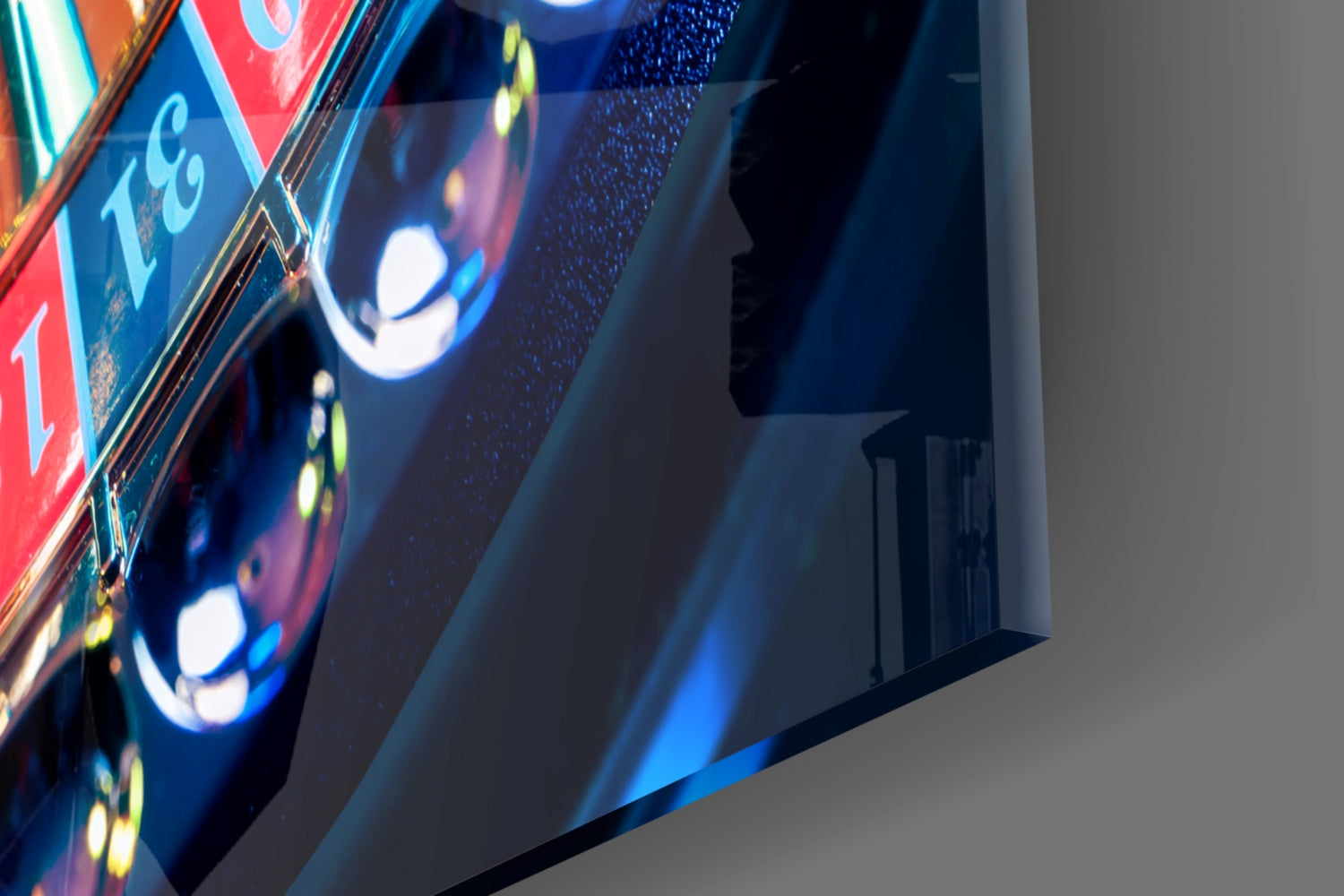 Close-up angled view of illuminated roulette wheel glass art with red and blue sections, bright white lights, and yellow text on dark background.