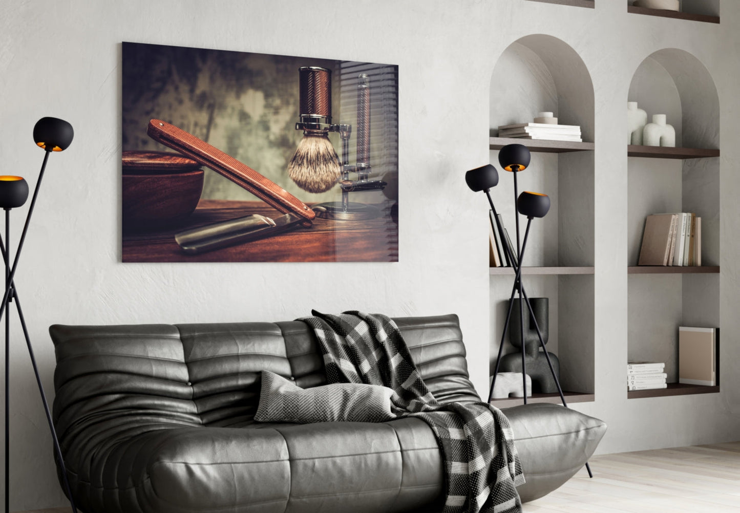 Vintage shaving tools photograph displayed above gray leather sofa in modern living room with arched wall shelving.