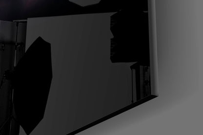 Close-up side view of black glass wall art panel with silhouetted deep-sea fish design against gray background.