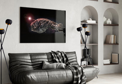Black framed glass wall art depicting a glowing deep-sea fish displayed above a gray leather sofa in a modern living room.