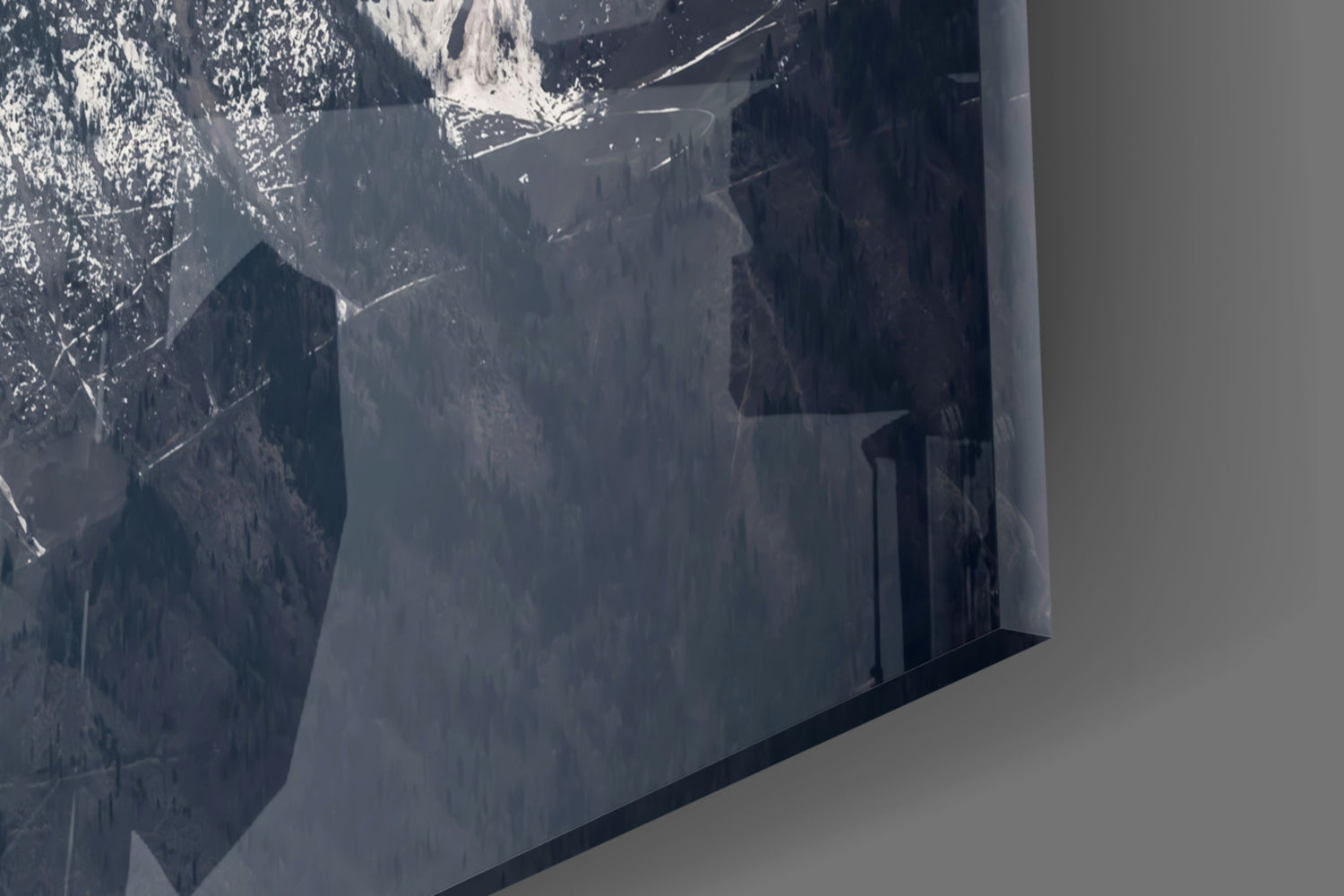 Close-up of frosted glass panel showing snowy mountain peaks and forested valleys in grayscale tones.