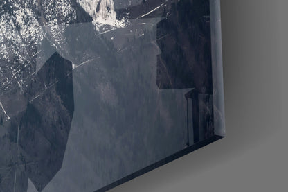 Close-up of frosted glass panel showing snowy mountain peaks and forested valleys in grayscale tones.