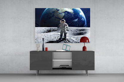 Space Walk Glass Wall Art displaying astronaut on lunar surface with Earth rising, mounted above gray media console in modern interior setting.