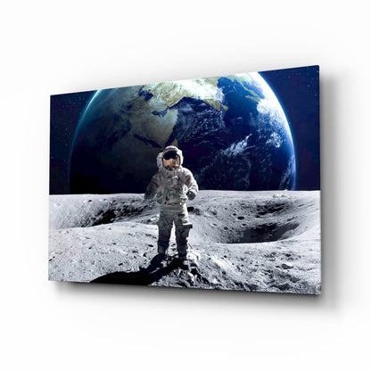 Astronaut in white spacesuit standing on lunar surface with Earth rising behind, displayed as glass wall art with 3D perspective effect.