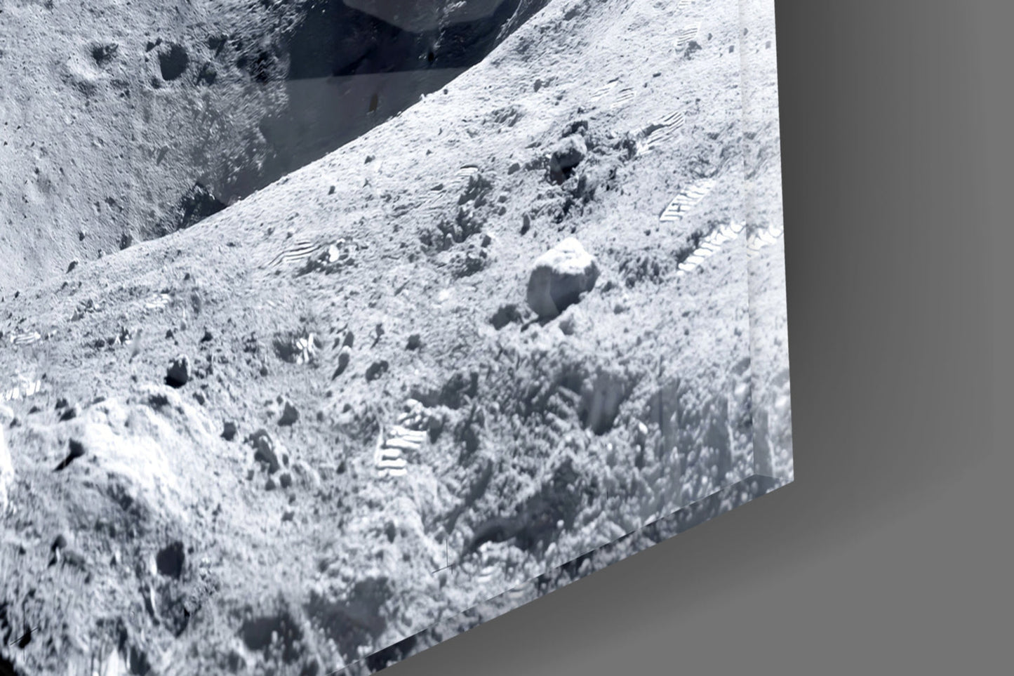 Close-up detail of lunar surface texture showing gray regolith, craters, and footprints on glass wall art panel.