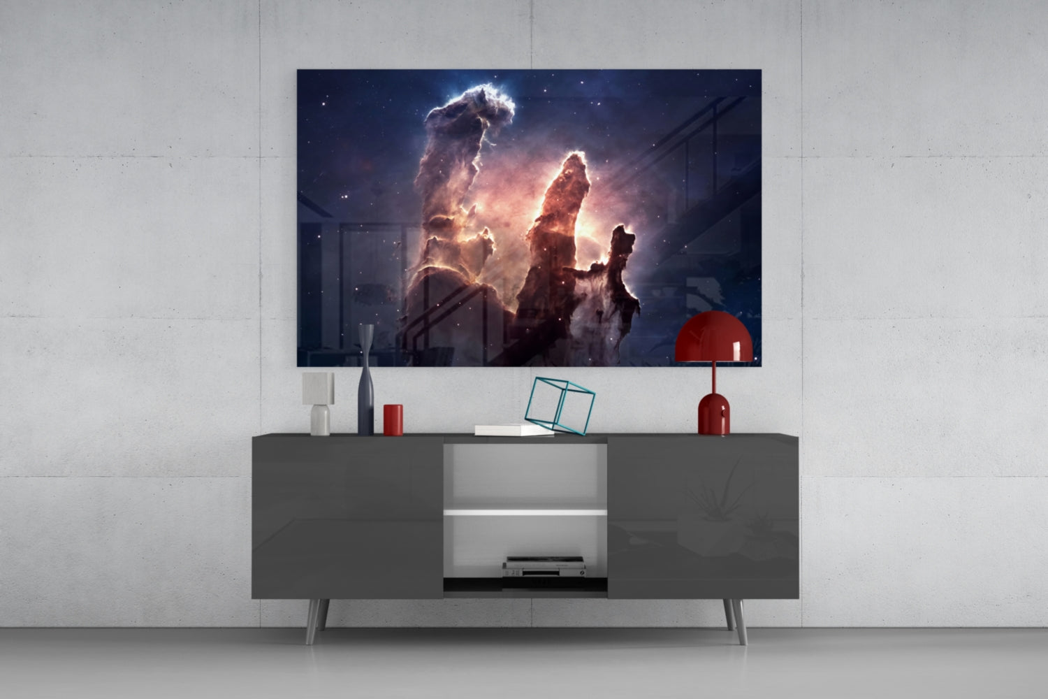 Modern living room setup featuring glowing nebula glass wall art displaying illuminated cosmic dust pillars above a dark gray media console with red decorative accessories.
