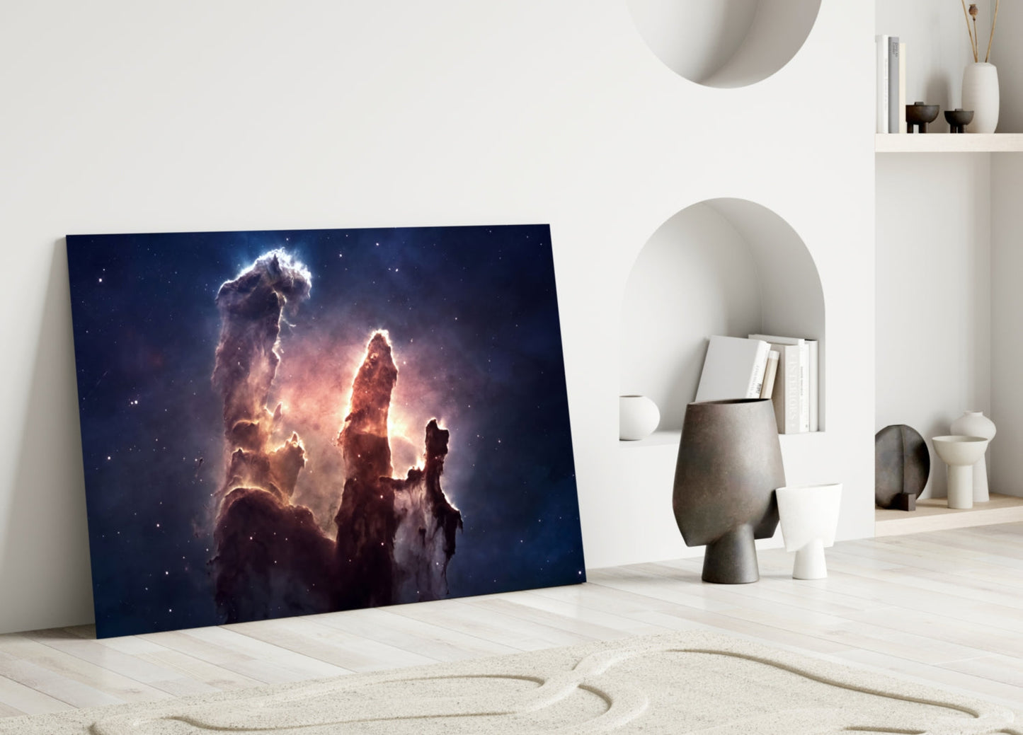 Space Clouds Glass Wall Art leaning against white wall in minimalist interior with sandy floor and decorative objects.